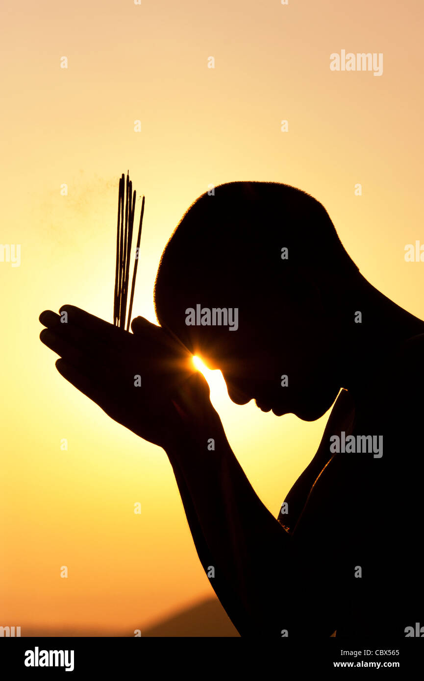 Beten mit Weihrauch indischen Mann klebt bei Sonnenuntergang. Silhouette. Indien Stockfoto