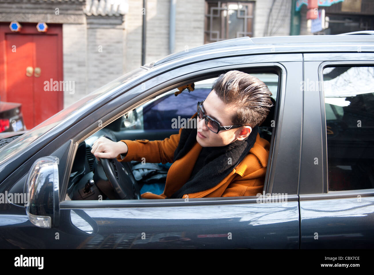 Beijing, junge Fahrer aus seinem Fenster während der Fahrt in einem schmalen Hutong Straße suchen. Stockfoto