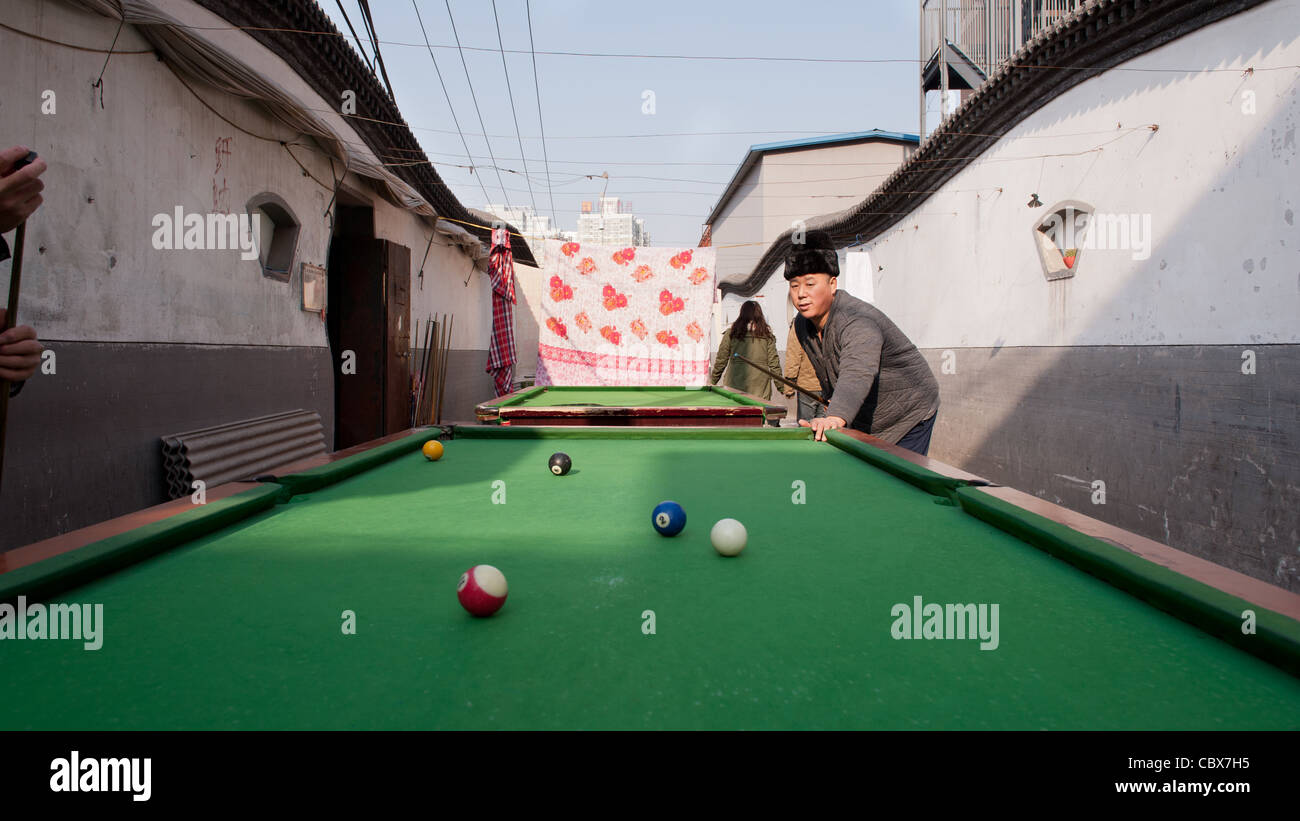 Xiadian, Beijing. Mann spielen Pool in einem Armenviertel mit in den Hintergrund Beijing Central Business District. Stockfoto