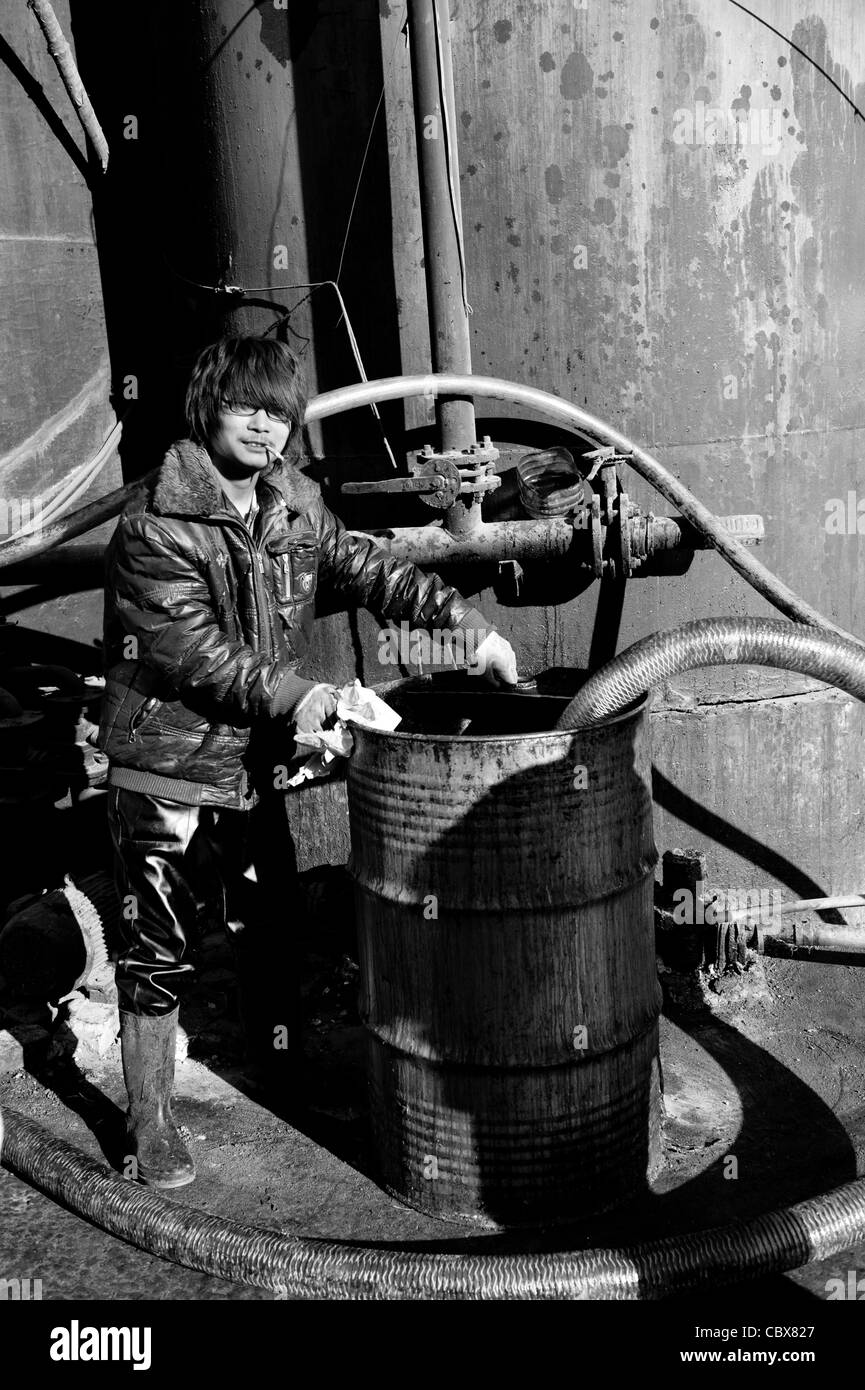 DongBaXiang, Beijing. Junger Mann bei einer Anlage für das recycling Speiseöl zu arbeiten. Stockfoto