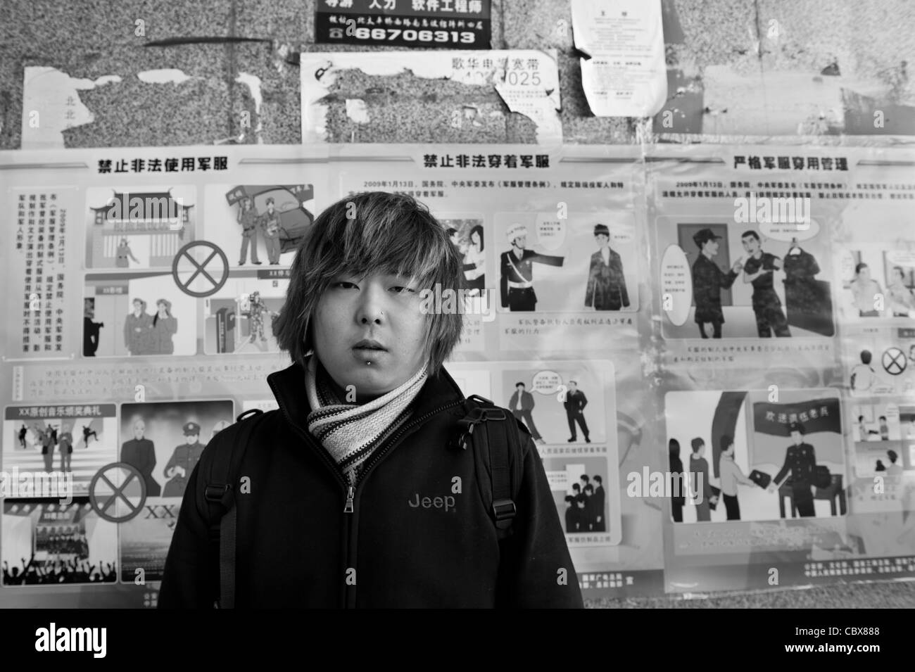 Beijin. Dong-Nan, Gitarrist in der Straße-Punk-Band "Warum Vernunft", vor dem Gebote und Verbote Plakat der Regierung. Stockfoto