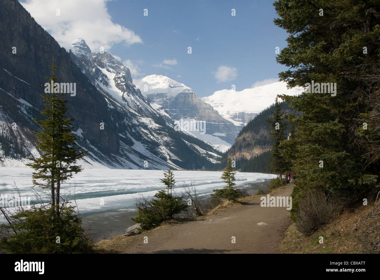 Trail neben gefrorenen See und Berge, Lake Louise, Banff, Alberta, Kanada Stockfoto