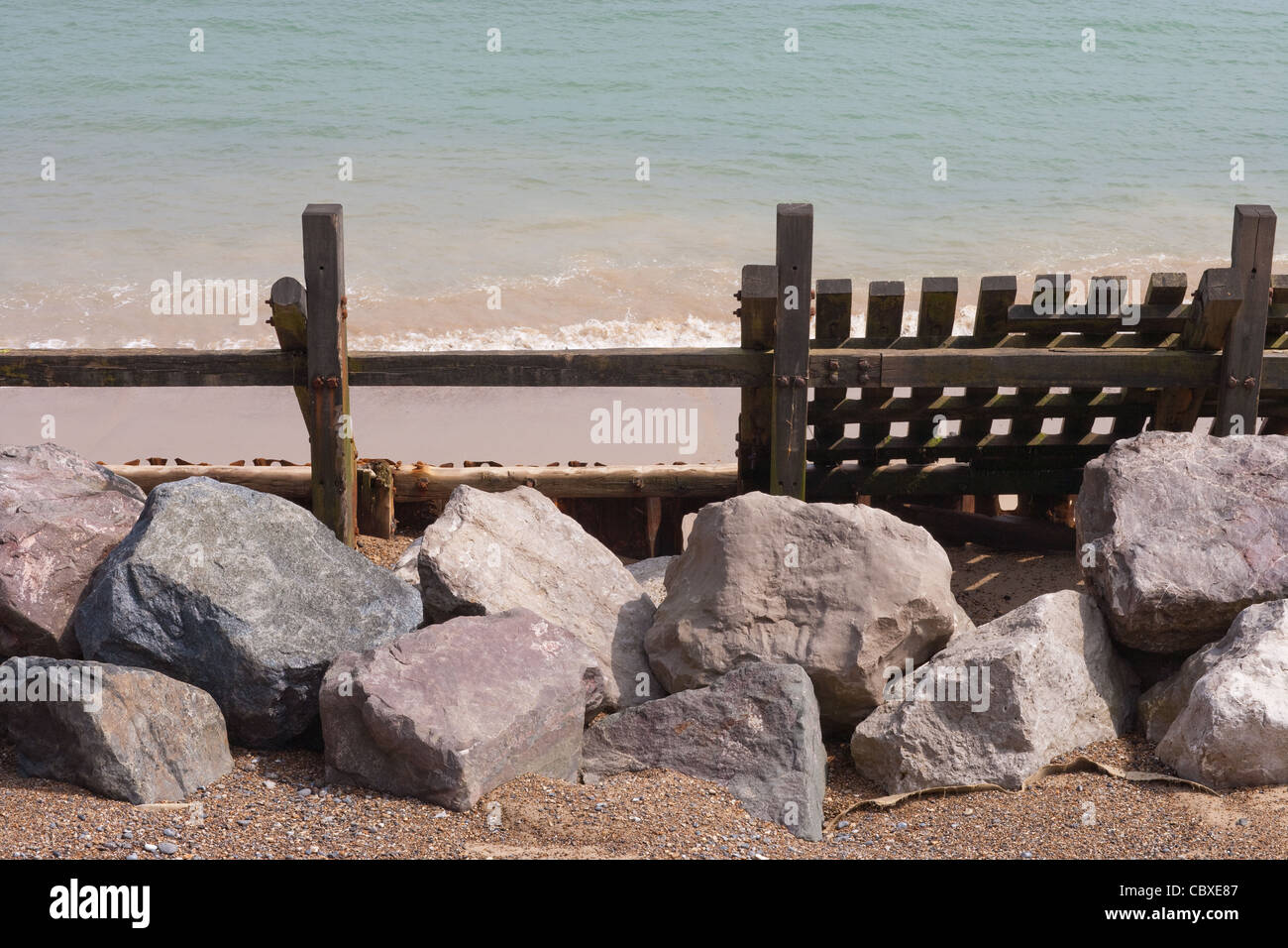 Happisburgh Strand. Norfolk. East Anglia. Überreste des Meeres beschädigt Holz Wellenbrecher mit importierter Granitfelsen, Vordergrund. Stockfoto