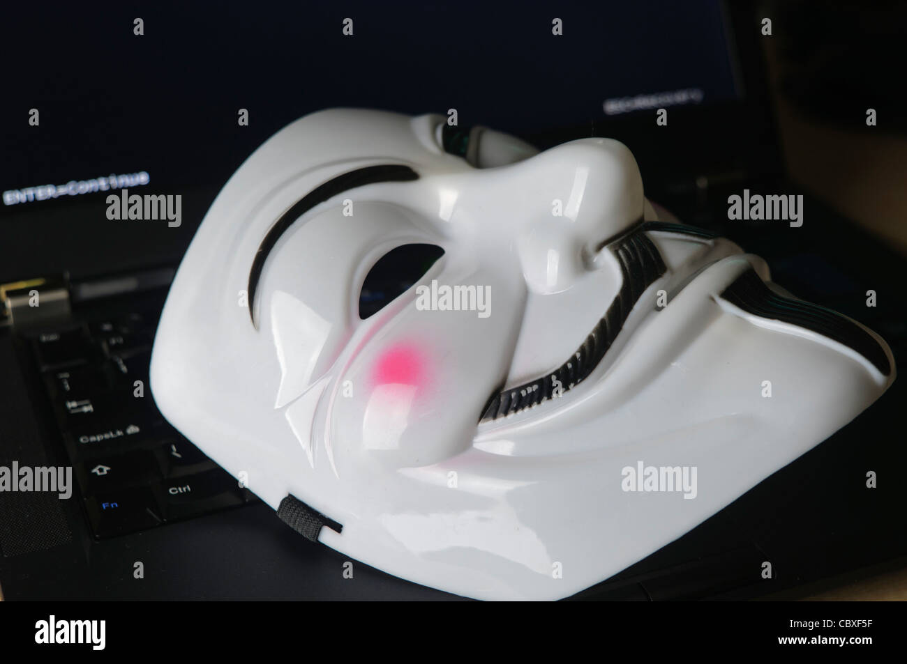 Maske von der Hacker-Gruppe "Anonymous" liegen auf einer Computertastatur Stockfoto