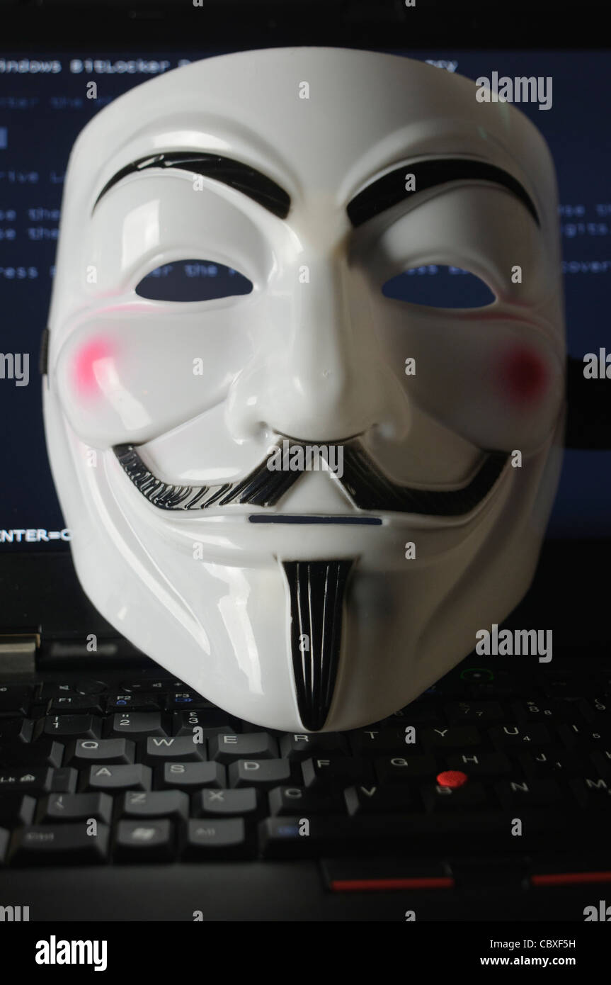 Maske von der Hacker-Gruppe "Anonymous" liegen auf einer Computertastatur Stockfoto