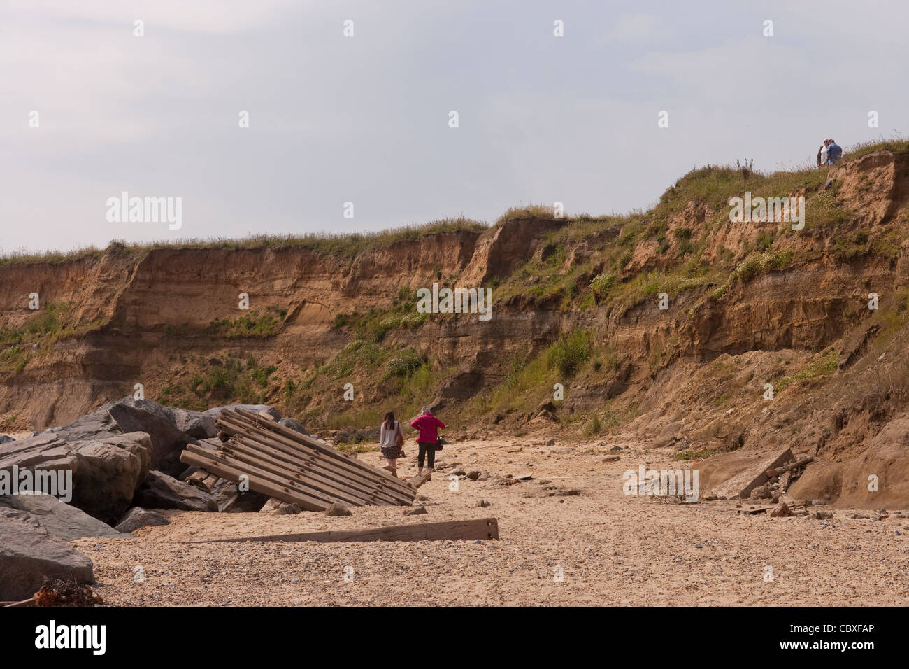 Happisburgh Küste, North Norfolk, East Anglia. Erosion der Felsen an der Nordsee; Menschen unter den zerstörten Küstenschutzes. Stockfoto