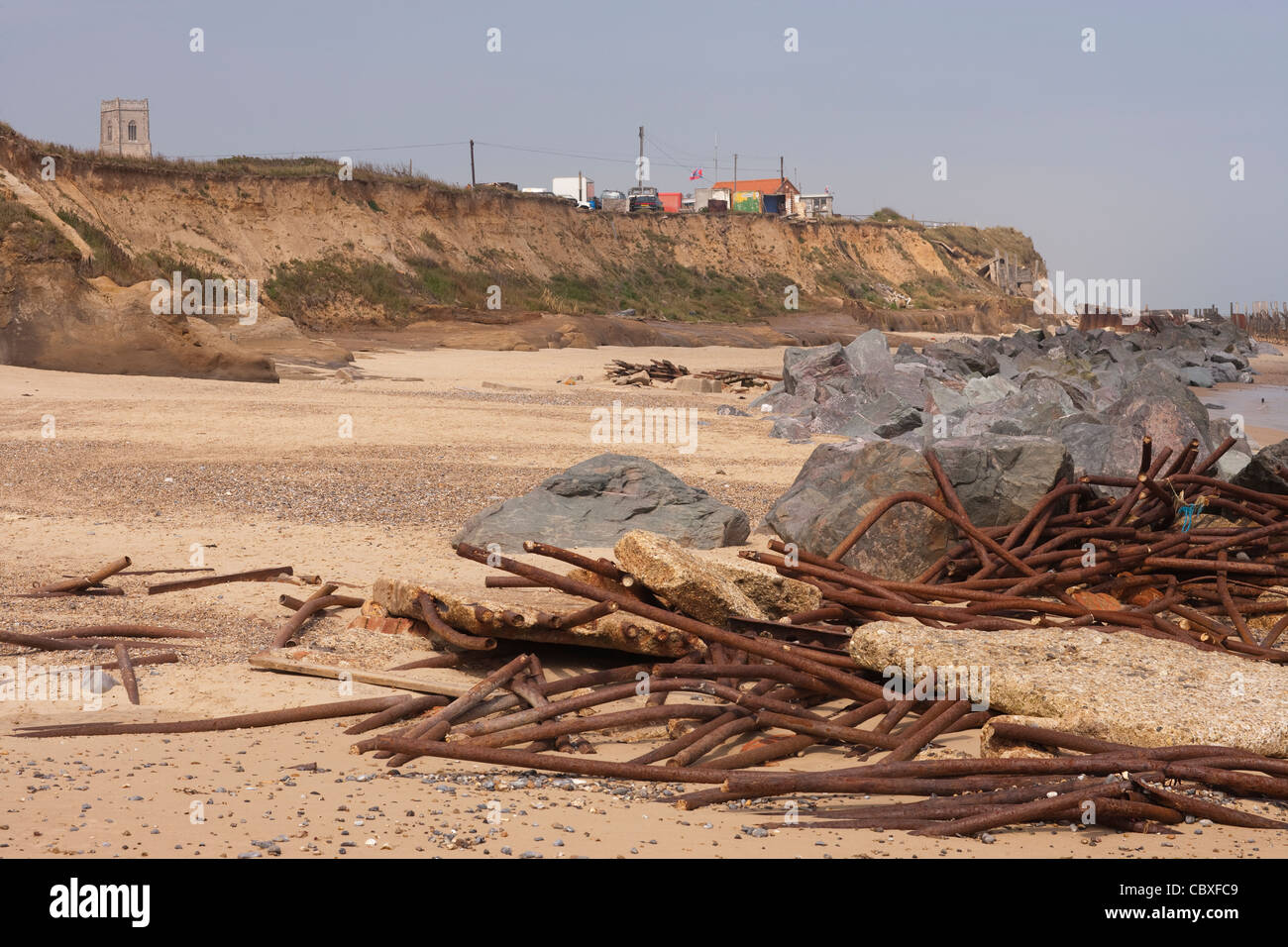 Happisburgh Strand und Klippen, North Norfolk. Flut zerstört Metall Brakewaters gegen importierter Granitfelsen angesammelt. Stockfoto