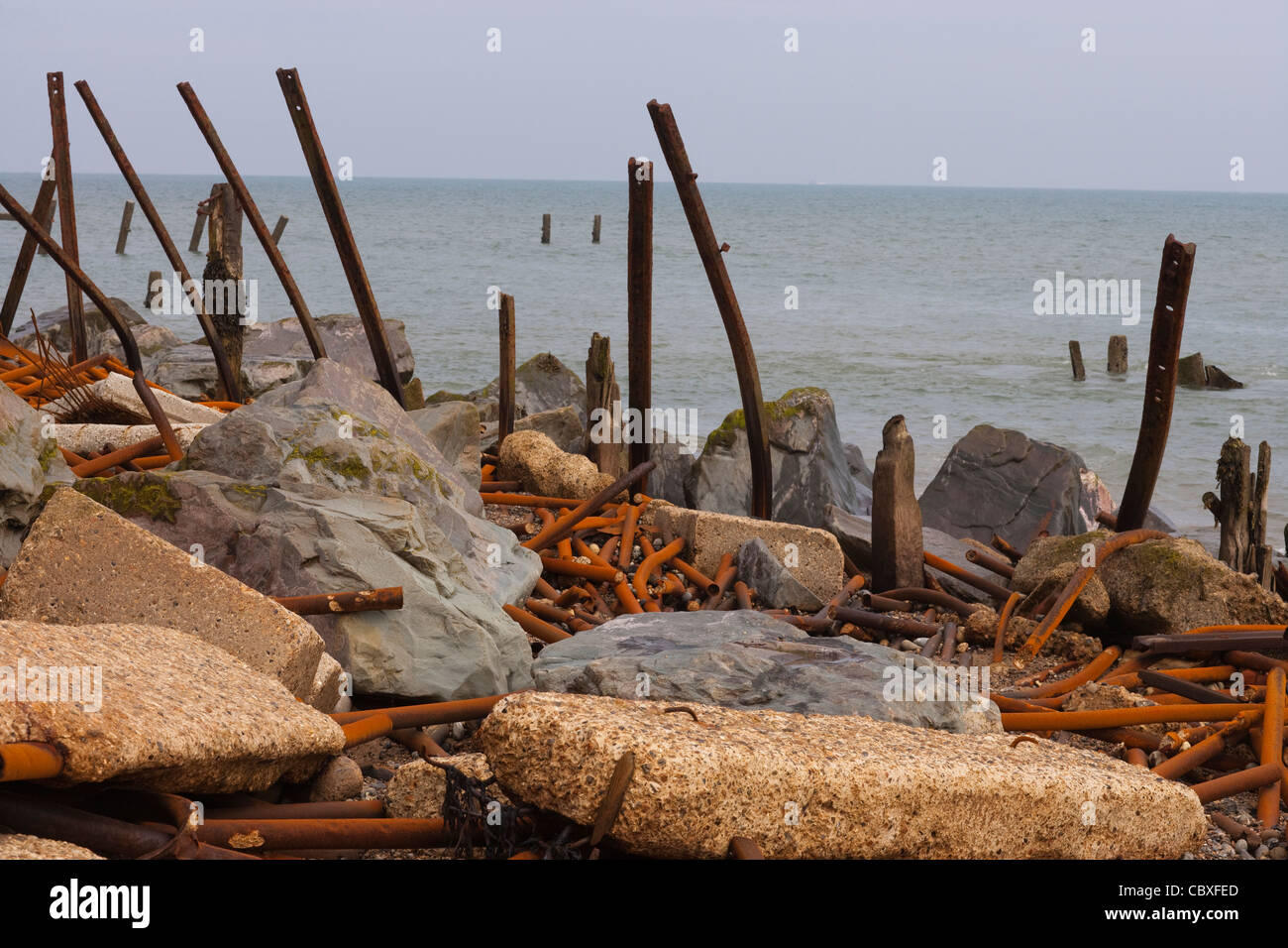 Happisburgh Beach, North Norfolk. Überbleibsel aus Metall Brakewaters durch Kraft der ankommenden Gezeiten zerstört. Rock und konkrete Blöcke. Stockfoto