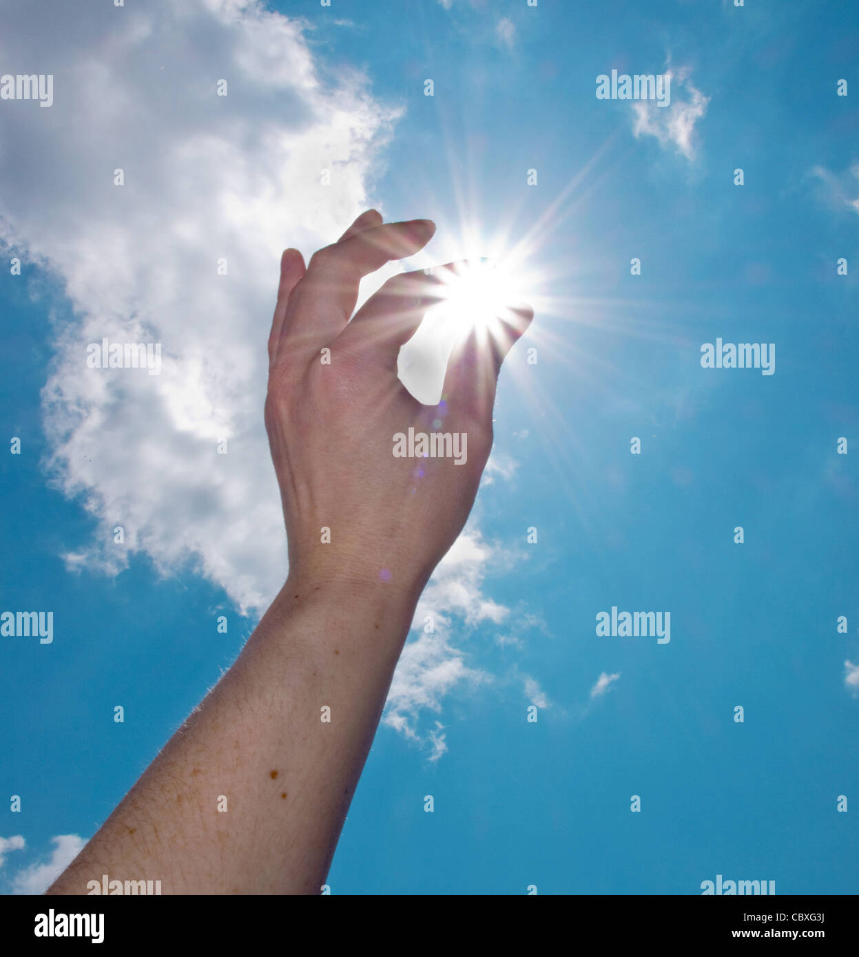 einer Hand fangen die Sonne am blauen Himmel Stockfoto