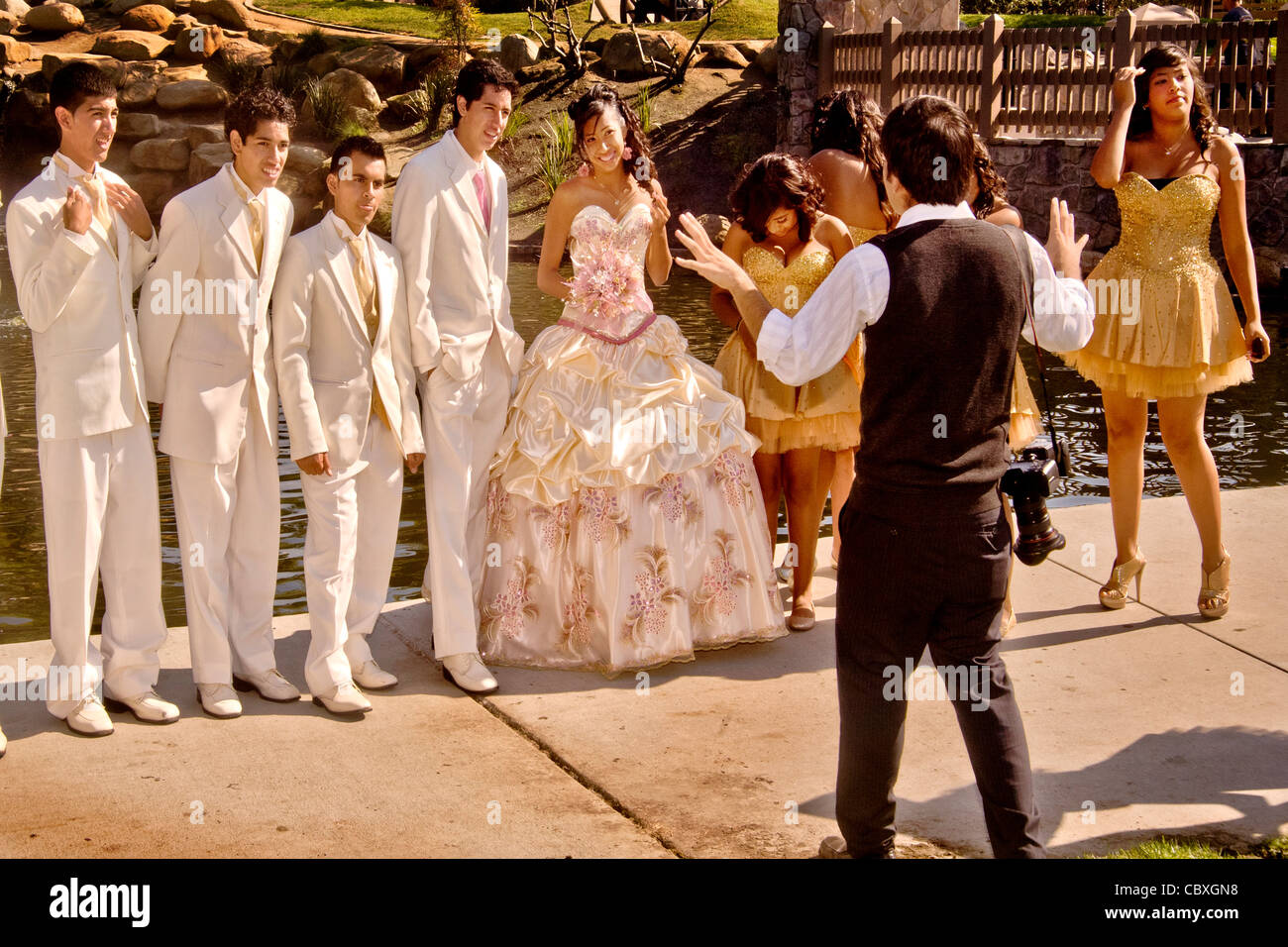 Ein formal gekleidete Mädchen in einem Cerritos, Kalifornien, stellt Park für einen Fotografen mit ihrem Hofstaat der Ehre an ihre Quinceanera Stockfoto