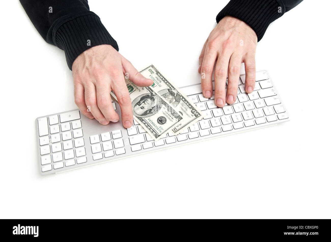Man tippt auf Tastatur, einige Dollar-Banknoten vor ihm Stockfoto