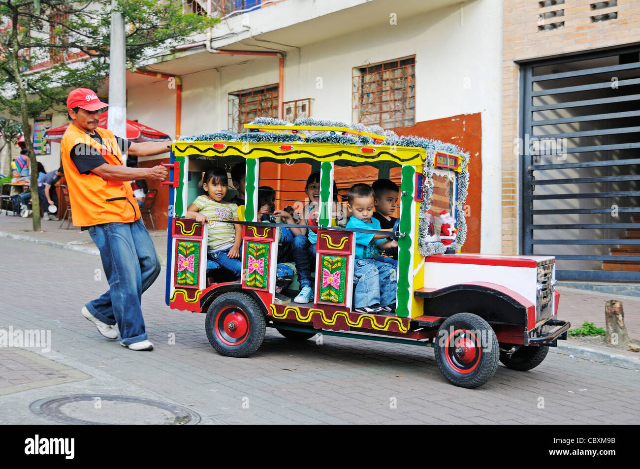 Man drückt ein Spielzeugauto mit Kindern, Plaza Biblioteca España, Comuna 13, Medellin, Kolumbien, Lateinamerika Stockfoto Man drückt ein Spielzeugauto mit Kindern, Plaza Biblioteca España, Comuna 13, Medellin, Kolumbien, Lateinamerika Stockfoto
