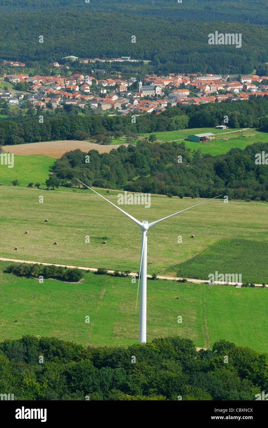 Luftaufnahme der Lichtmaschine und Propeller einer Windkraftanlage mit auf Hintergrund Kohle-Kraftwerke und französisches Dorf Stockfoto