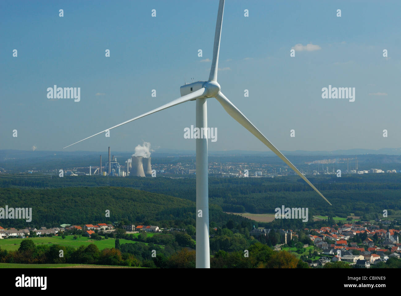 Luftaufnahme der Lichtmaschine und Propeller einer Windkraftanlage mit auf Hintergrund Kohle-Kraftwerke und französisches Dorf Stockfoto