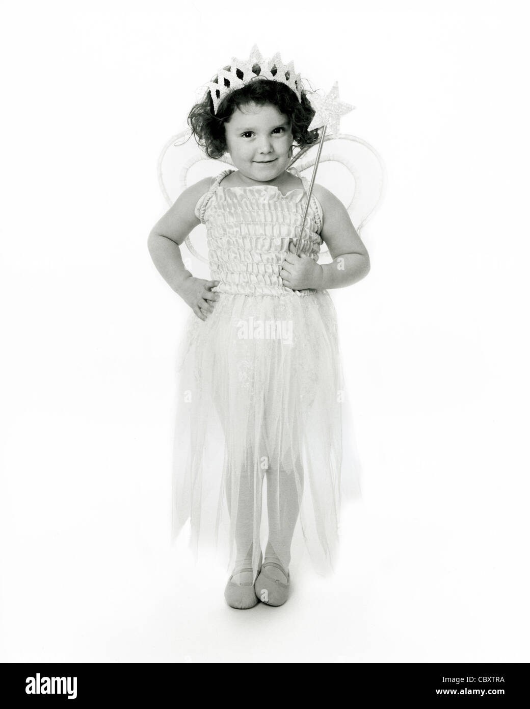 Monochrome, hochtakte Studioaufnahme eines jungen kaukasischen Kindes, das in einem Feenkostüm mit Flügeln und einem Zauberstab gekleidet ist. Stockfoto