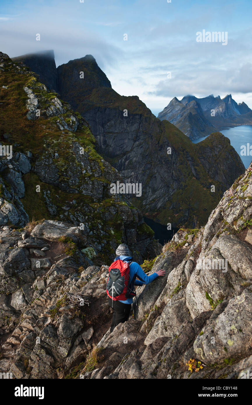 Weibliche Wanderer erklimmt Felsen auf Reinebringen, Lofoten Inseln, Norwegen Stockfoto