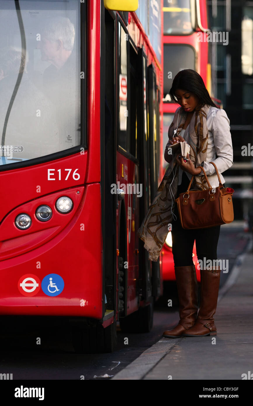 eine junge Frau ihr Fahrgeld vor dem Einsteigen in eines roten Londoner Bus überprüfen Stockfoto eine junge Frau ihr Fahrgeld vor dem Einsteigen in eines roten Londoner Bus überprüfen Stockfoto