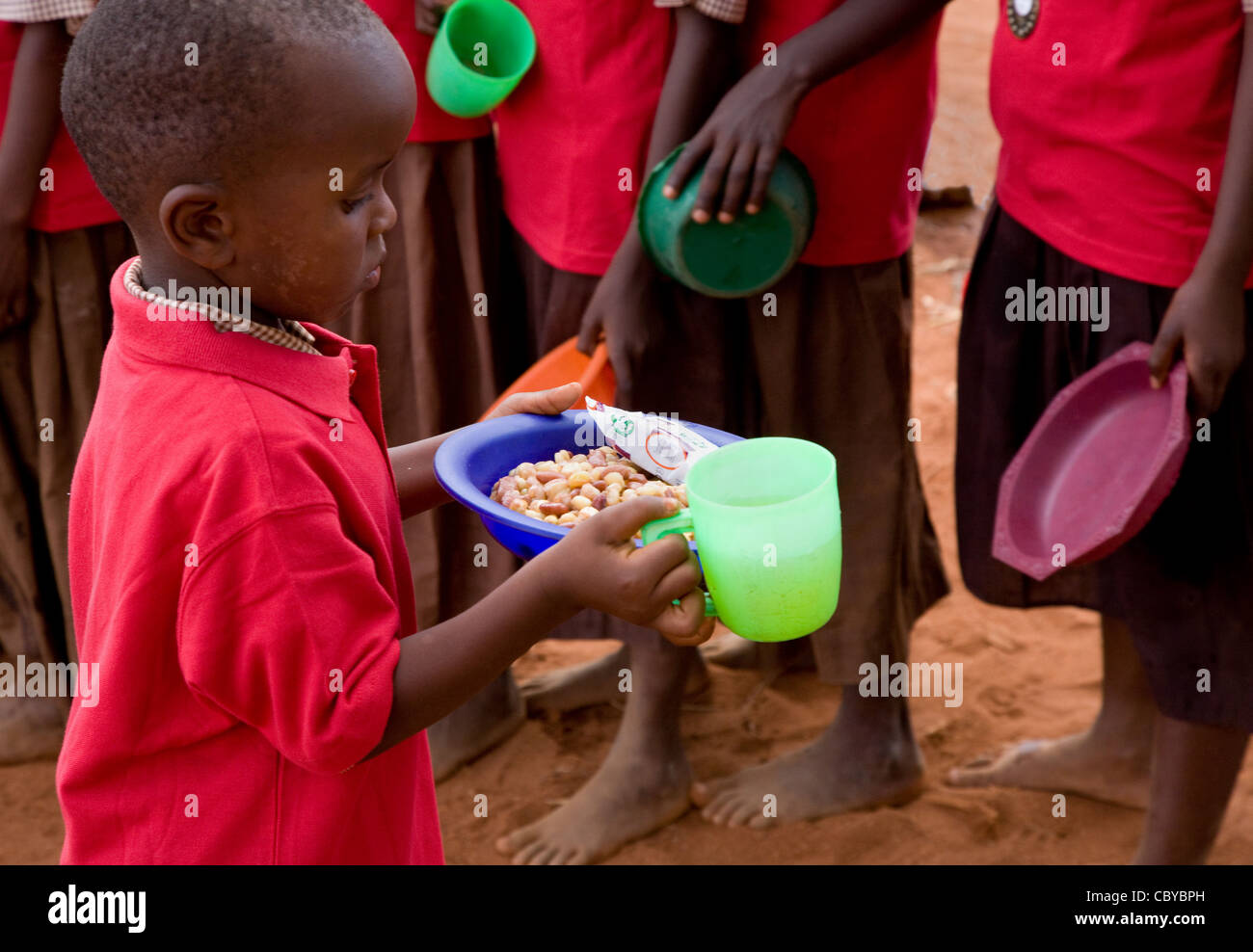 Ein Kind in einer kenianischen Schule mit seinem Mittagessen übergibt Abendessen Warteschlange an Kileva Easfield Primary School in der Nähe von Voi Stockfoto