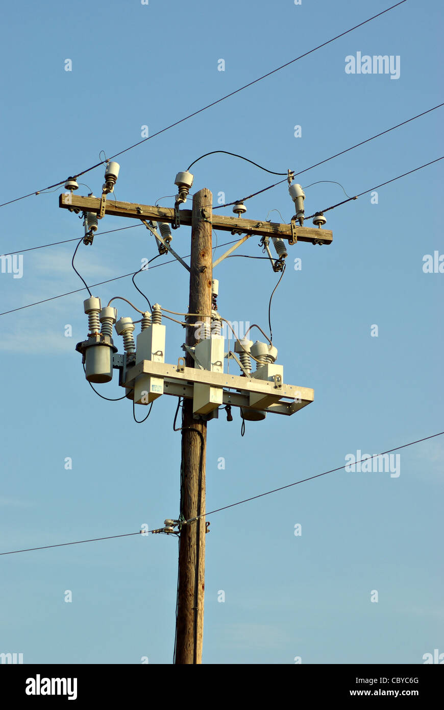 Ein Bild von Stromleitungen vor einem blassen blauen Himmel. Stockfoto