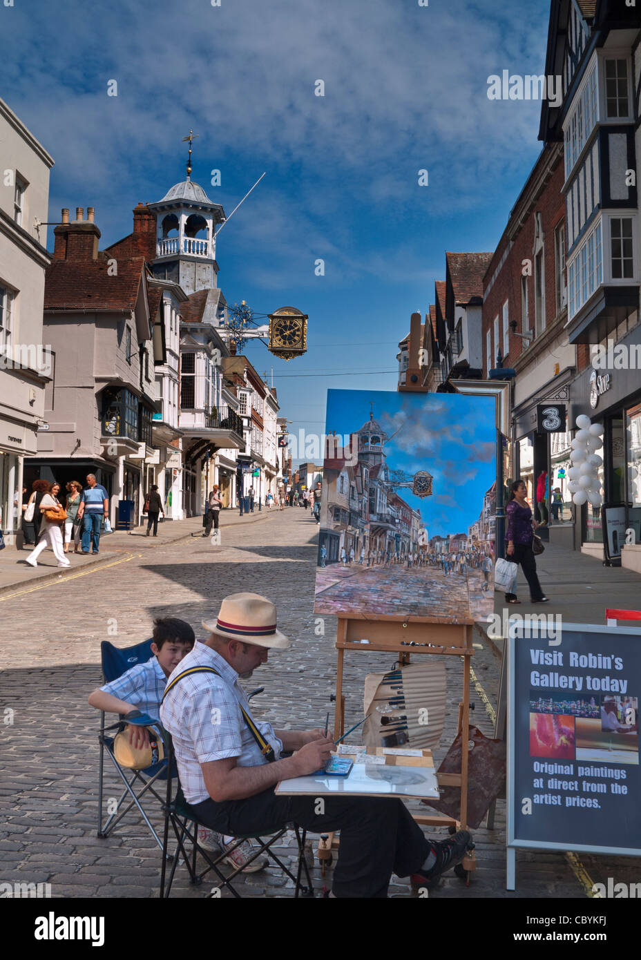 GUILDFORD KÜNSTLER HIGH STREET MALEREI ANSICHT Aquarell Arbeit historischen gepflasterten Fußgänger Guildford High Street & ikonische Uhr mit Käufern Surrey UK Stockfoto