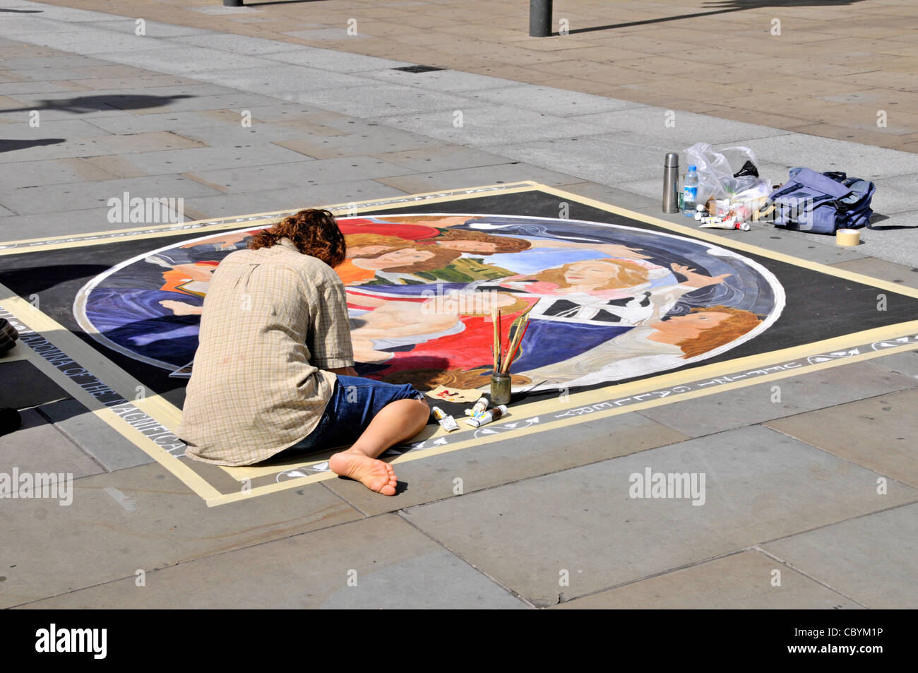 Sonniger Tag Straßenszene Rückansicht Künstlerin Person arbeitet und sitzt, die Kunst auf Straßenplatten im Tourismusbereich Trafalgar Square London England Vereinigtes Königreich schafft Stockfoto