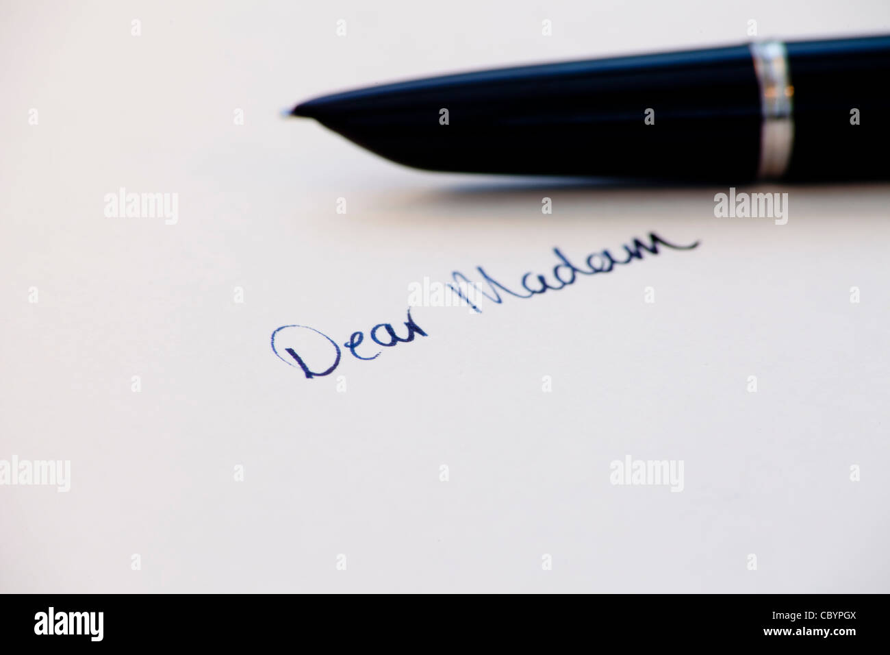 die Worte "Sehr geehrte Frau" handschriftlich mit Tinte mit Füllfederhalter im Hintergrund Stockfoto