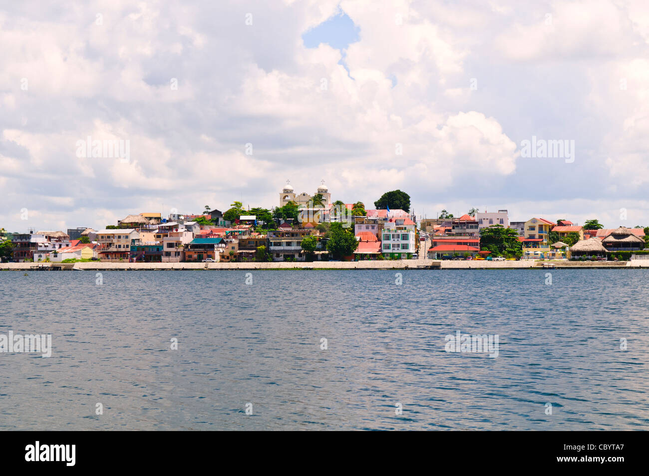 Flores Island Town Lake Peten Itza Guatemala // FLORES, Guatemala - Blick auf Flores, Guatemala, von einem Boot auf dem See Peten Itza. Die kleine Inselstadt Flores ist die Hauptstadt des nördlichsten Departements Guatemalas, Petén, und ist über einen Damm mit dem Festland verbunden. Der rund 32 Quadratkilometer große See Peten Itza umgibt die Siedlung aus der Kolonialzeit, die für ihre farbenfrohen Gebäude und engen Gassen bekannt ist. Flores ist ein beliebtes Tor für Touristen, die die nahe gelegenen Maya-Ruinen von Tikal besuchen. Stockfoto