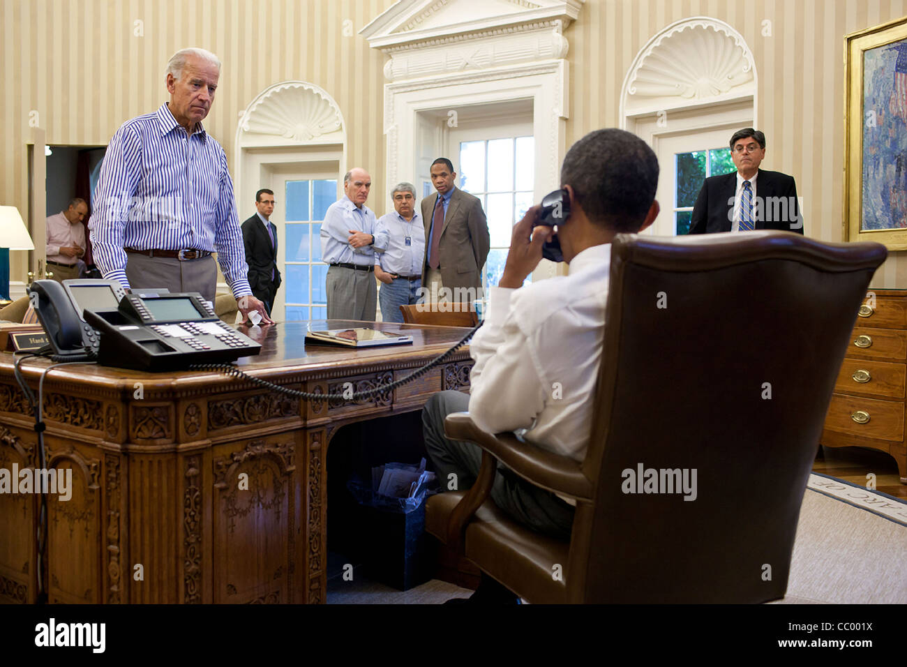 Vize-Präsident Joe Biden und andere Mitarbeiter sehen und hören, wie der Präsident Barack Obama am Telefon im Oval Office mit Senate Majority Leader Harry Reid während die Schulden begrenzen und Defizit Diskussionen 31. Juli 2011 in Washington, DC spricht. Stockfoto