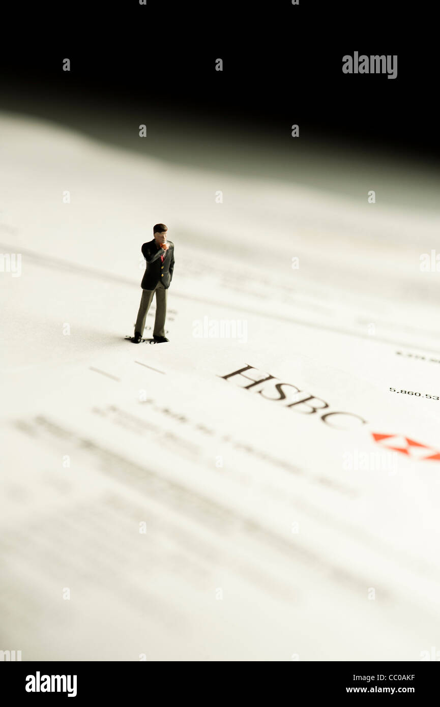 eine kleine Figur eines Mannes, der Blick auf einen Kontoauszug von HSBC Bank - Konzeptbild für Banking und finance Stockfoto