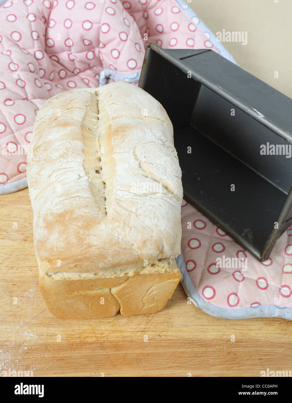 Englische Split-Zinn-Brot, frisch aus dem Ofen auf einem Holzbrett mit dem Backen Zinn und Ofen-Handschuhe Stockfoto