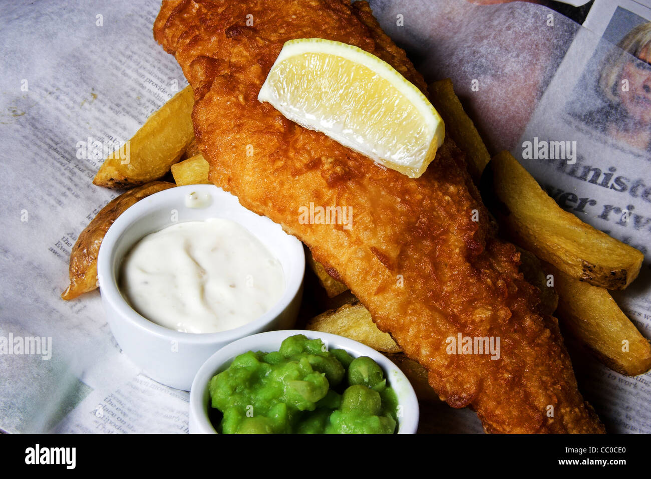 Tauchen Sie ein Fisch-Chips und Erbsen mit einer Scheibe Zitrone und Remoulade Stockfoto