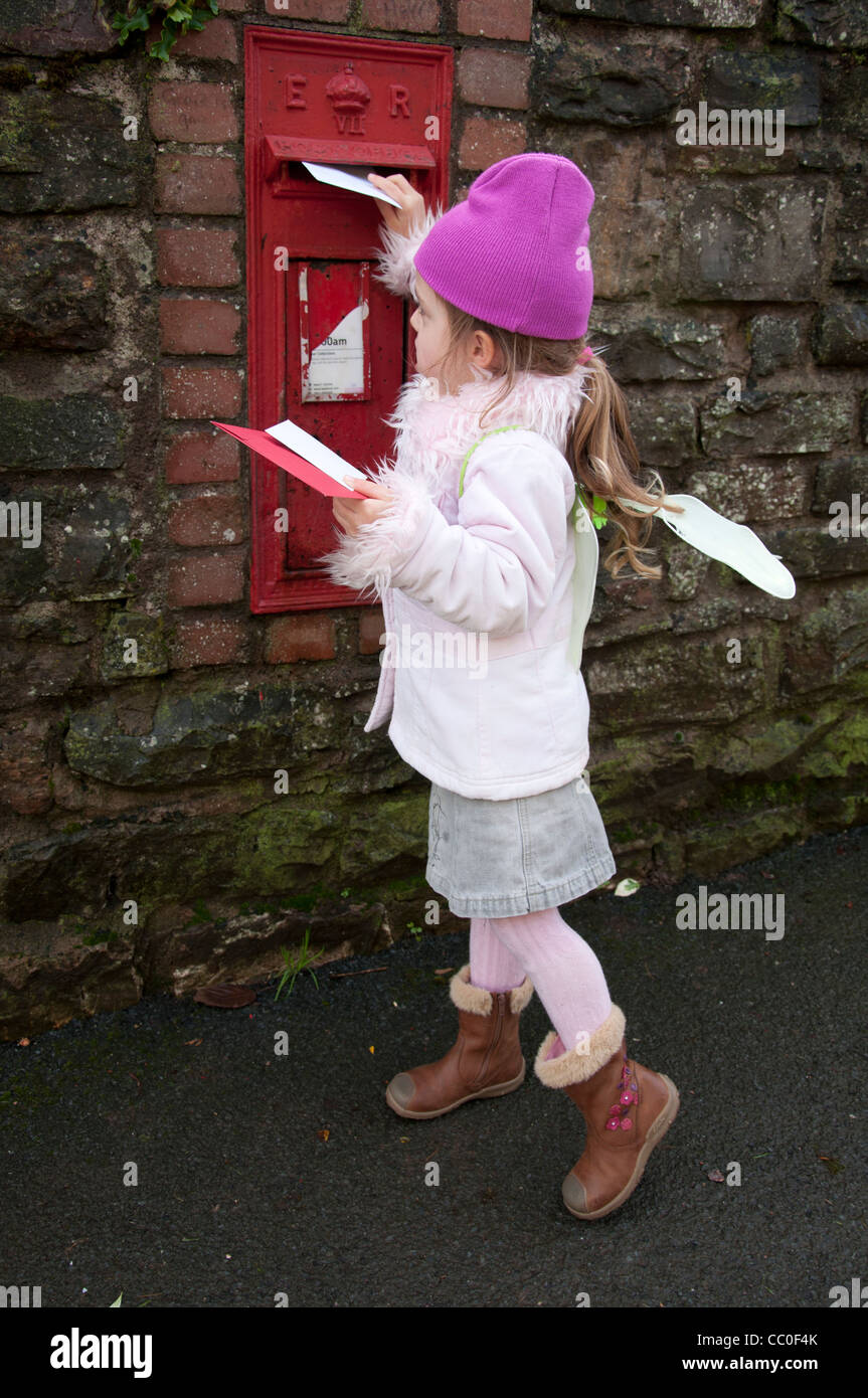 Kleines Kind, fünf Jahre altes Mädchen, Entsendung Weihnachtskarten in einer Royal Mail-Postfach. Stockfoto
