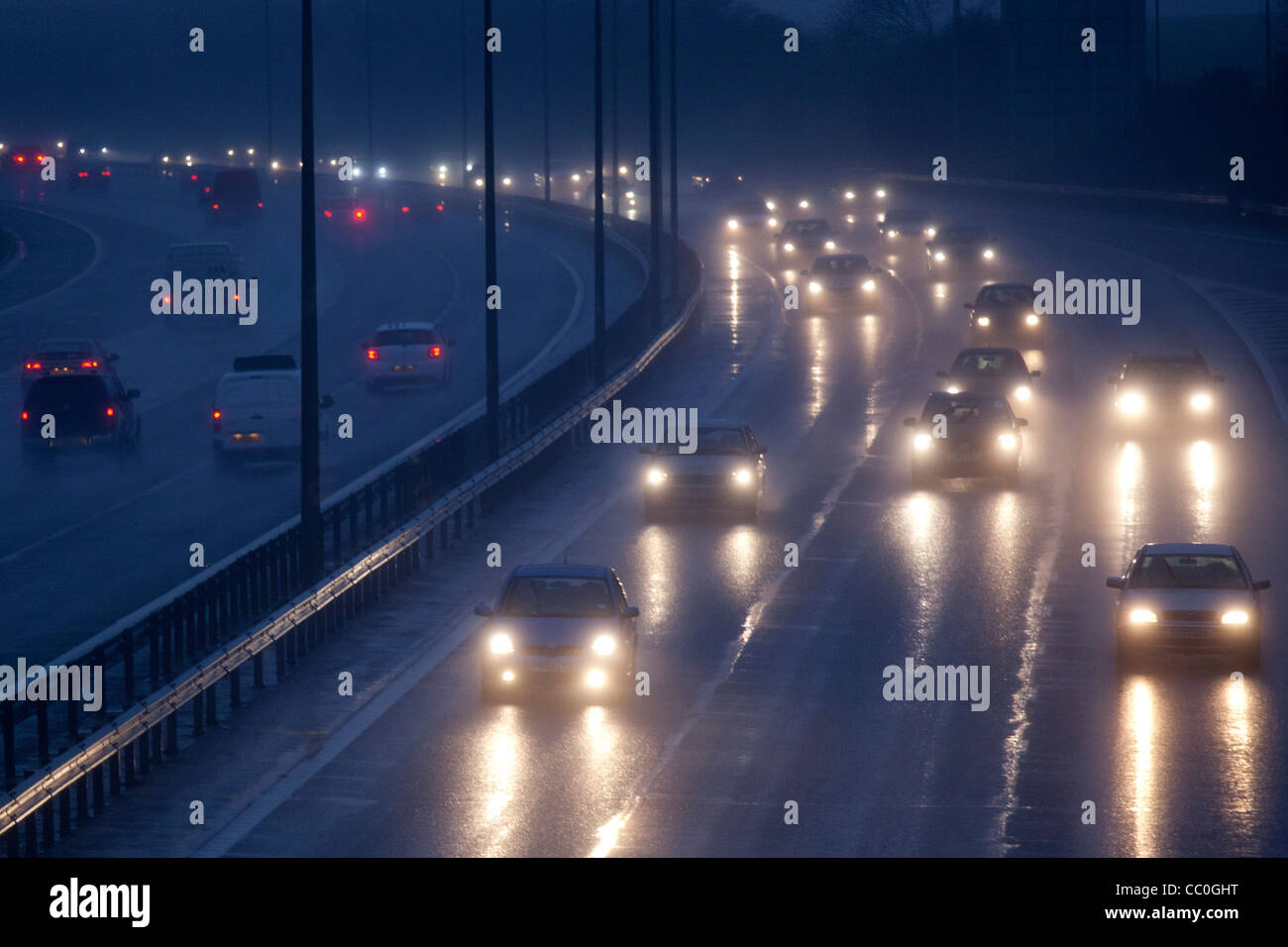 Auto und Verkehr auf einem nassen Abend auf Großbritannien Autobahn zu regnen. Autofahren in gefährlichen winterlichen Bedingungen. Stockfoto