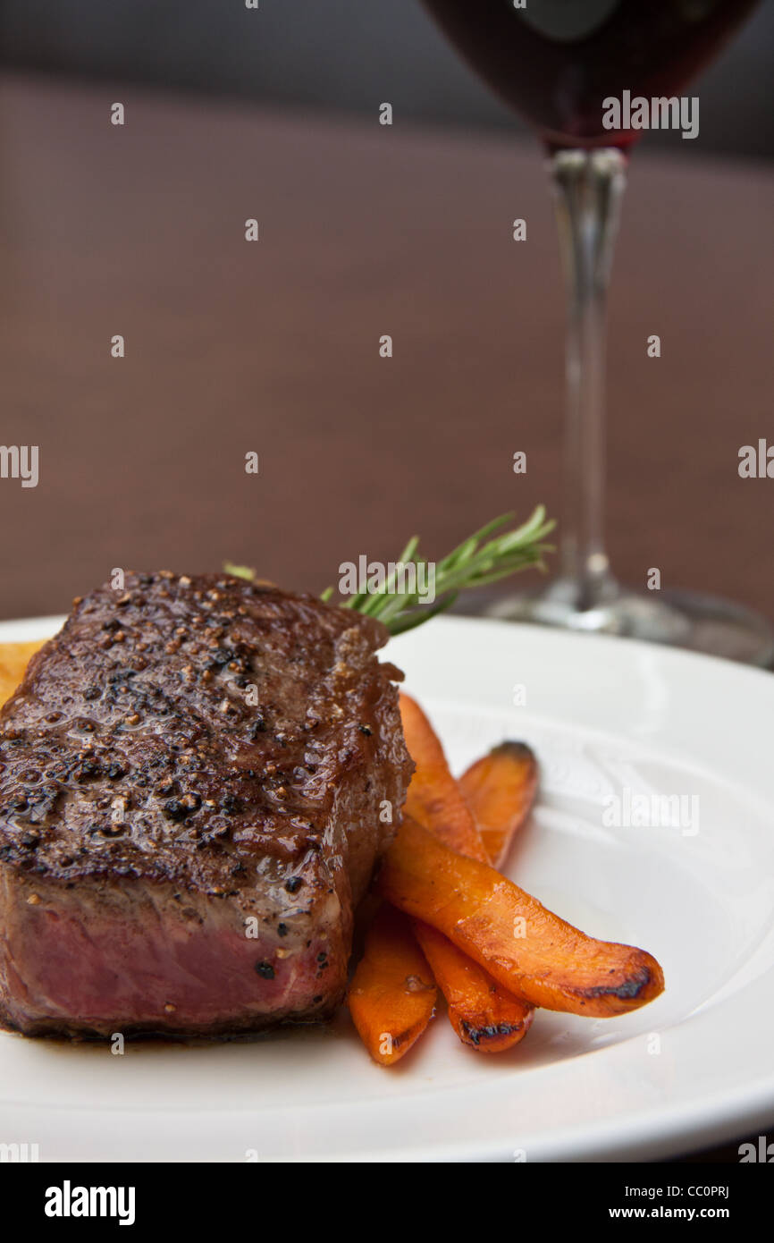 Pfefferkorn verkrustet Streifen Lende Steak über Kartoffeln Dauphiné und Sherry glasierte Babykarotten Stockfoto