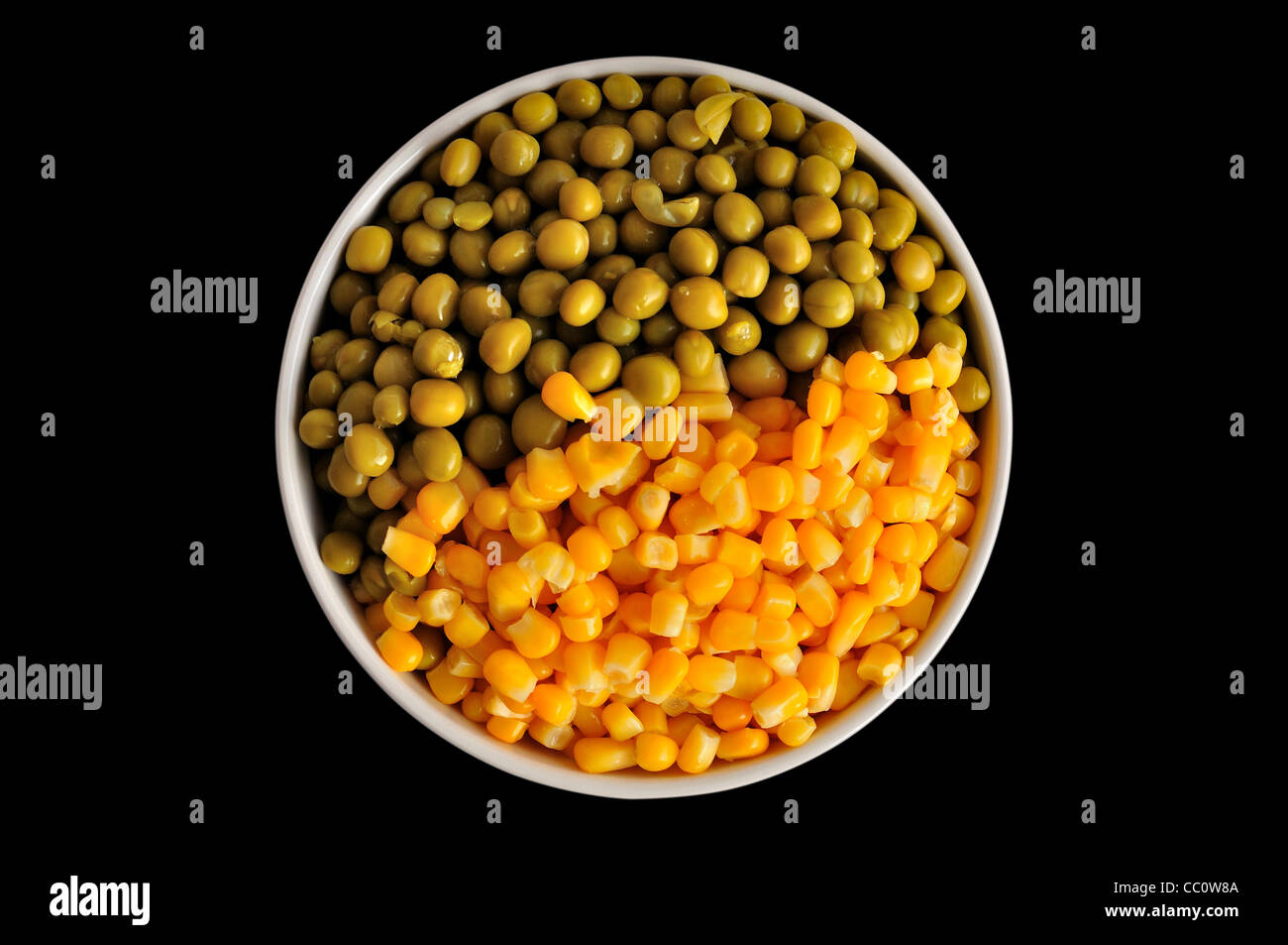 eine Platte mit Mais und Erbsen, isoliert, auf einem schwarzen Hintergrund Stockfoto