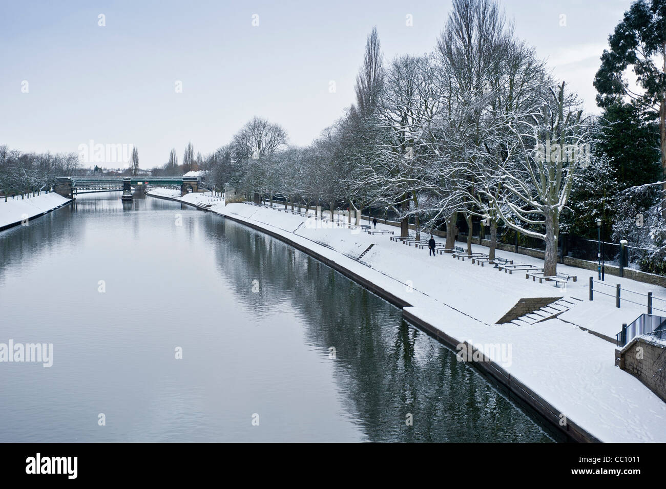 Schneebedeckte Dame Judi Dench Wanderung entlang des Flusses Ouse in York mit Scarborough Eisenbahnbrücke in der Ferne. Aufnahme von der Lendal-Brücke. Stockfoto