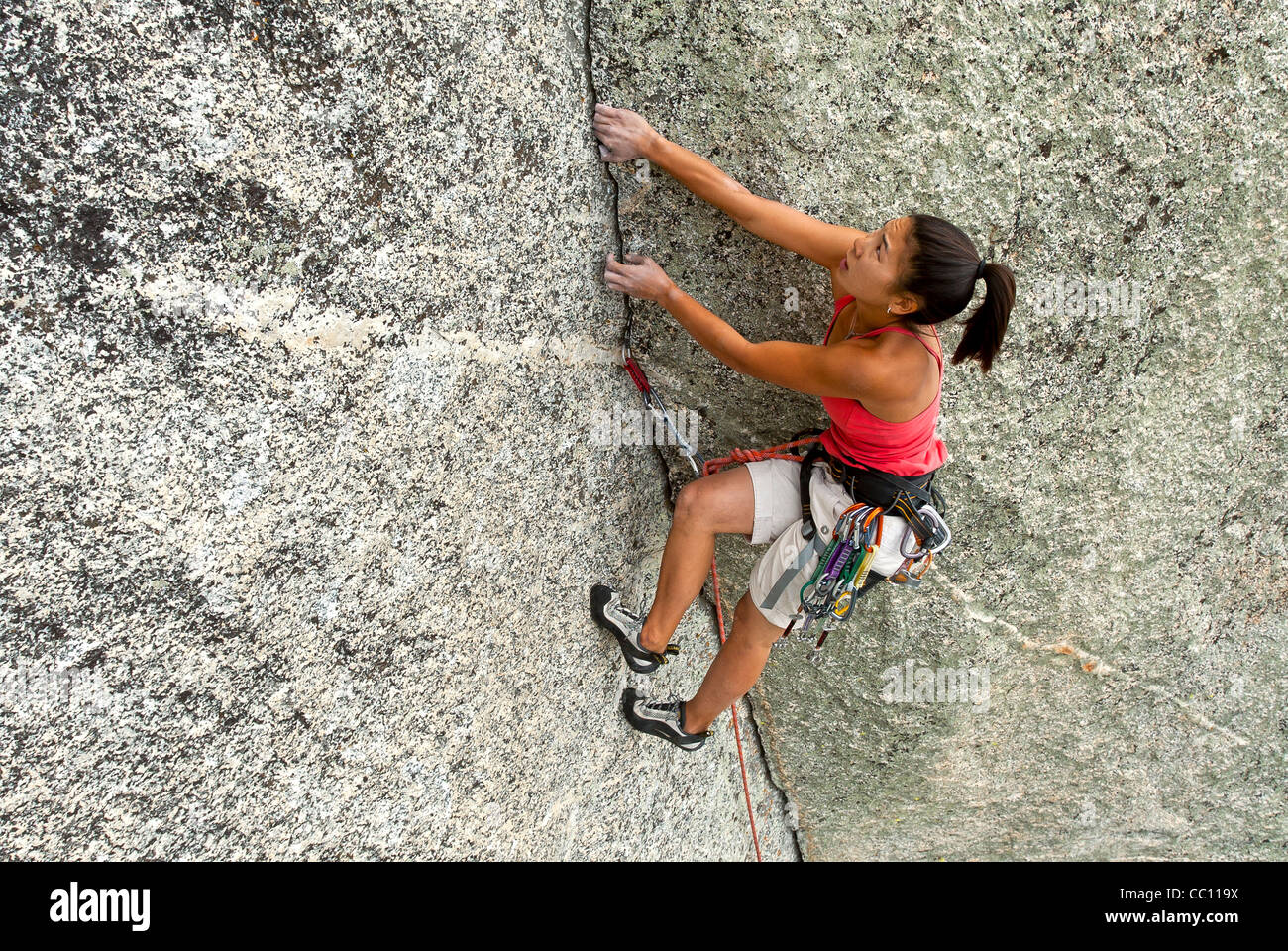 Weiblichen Rock Climber kämpft für ihren nächsten Griff am Rande einer steilen Klippe. Stockfoto