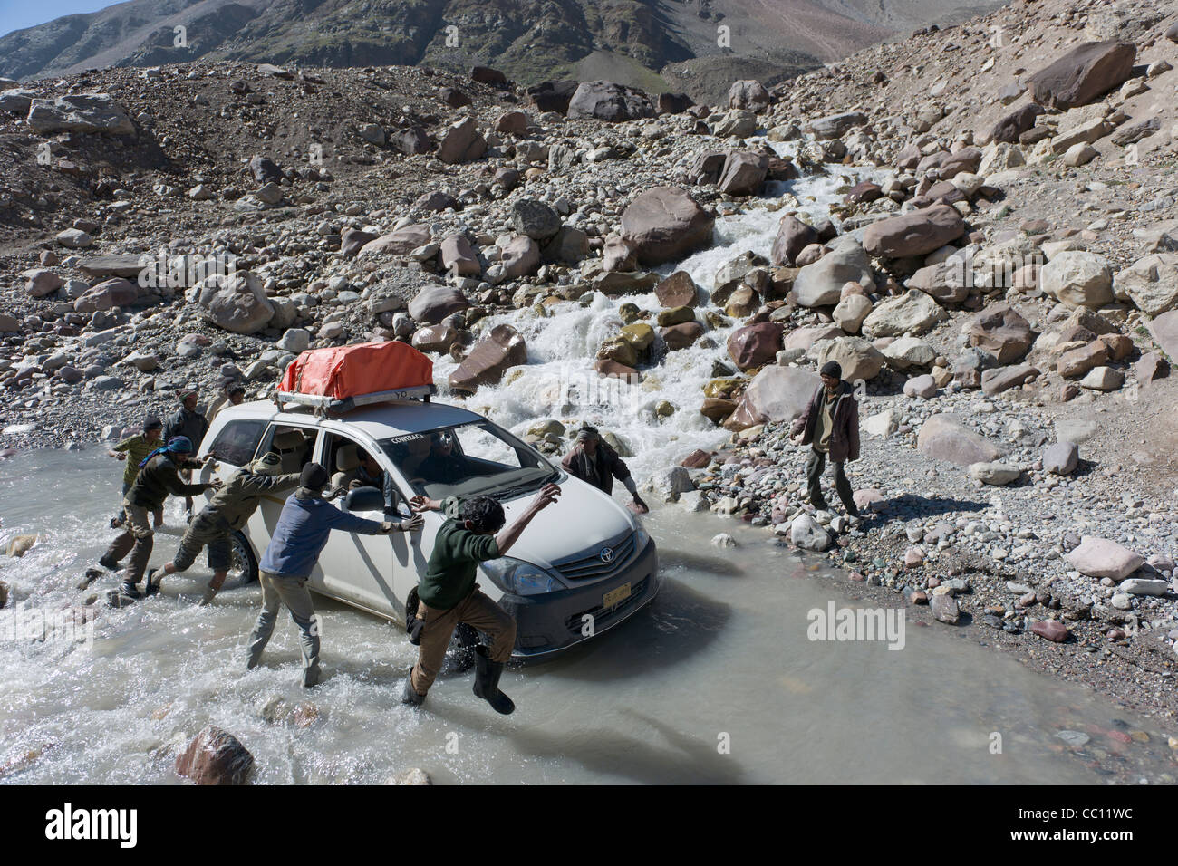 Straßenarbeiter schieben eine gestrandete Touristen-Fahrzeug durch einen Bach an der Manali-Leh Highway, Himachal Pradesh, Indien Stockfoto