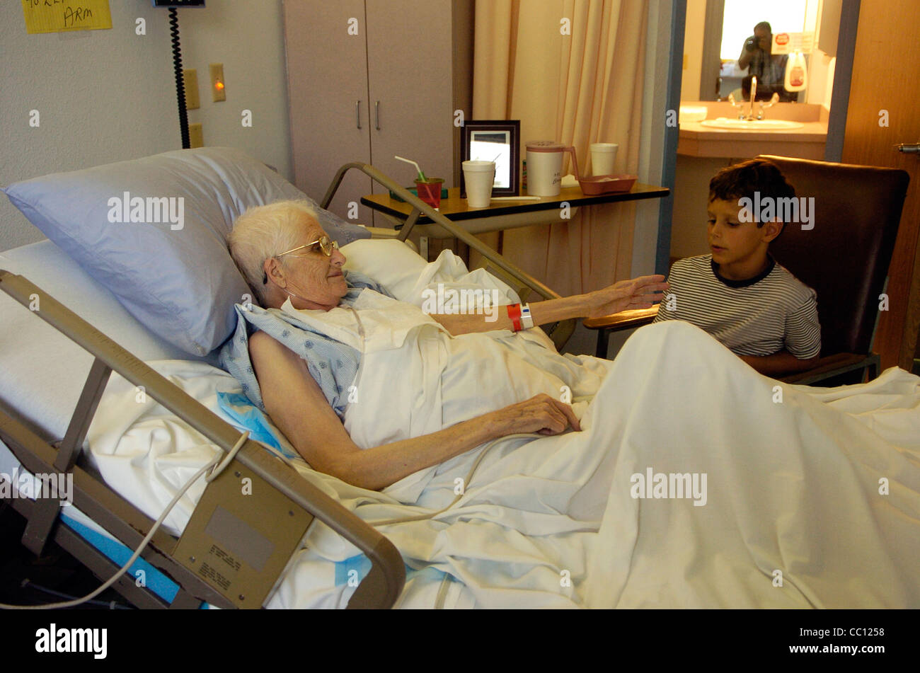 73 Jahre alte Anglo eingehakt mit Sauerstoff erhält Besuch von Enkel die lag sie im Krankenhausbett mit Krebs im Endstadium Stockfoto