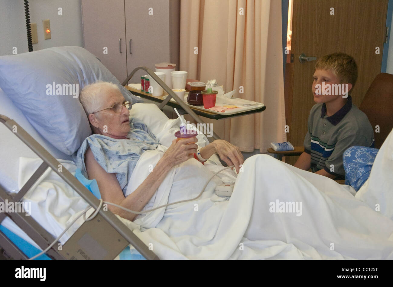 73 Jahre alte Anglo eingehakt mit Sauerstoff erhält Besuch von Enkel die lag sie im Krankenhausbett mit Krebs im Endstadium Stockfoto