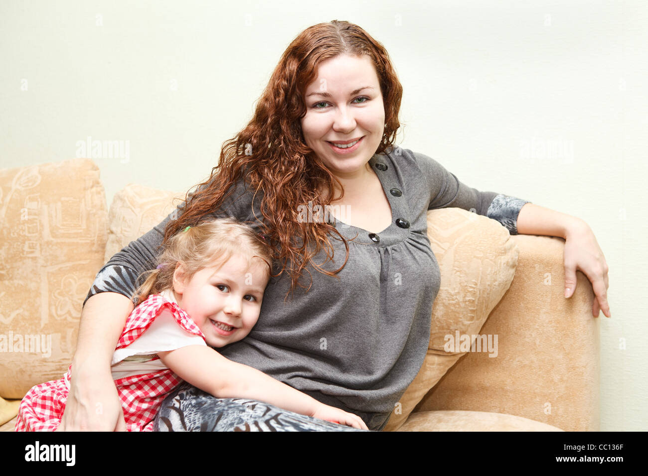 Mutter und ihre kleine Tochter sitzen und Couch und umarmt Stockfoto