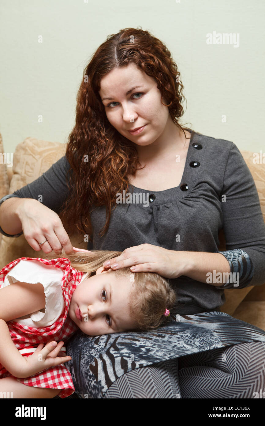 Mutter und Tochter auf der Couch sitzen. Frau Kämmen Tochter Haar Stockfoto