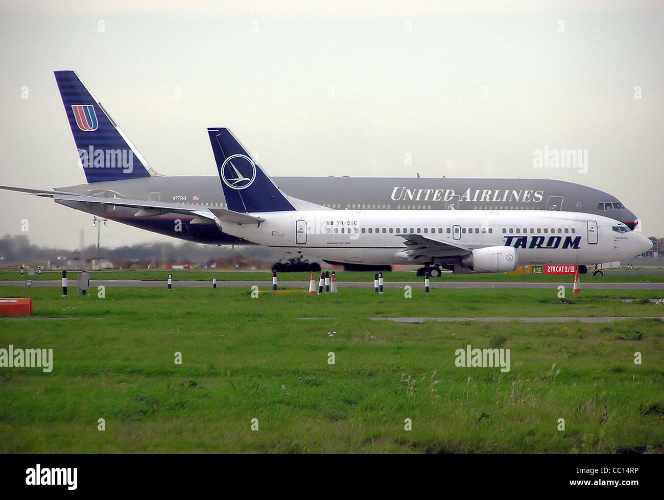 TAROM Boeing 737-300 (YR-BGC) und United Airlines Boeing 777-200 (N776UA) des Rollens Side by Side am Flughafen London Heathrow, Engla Stockfoto
