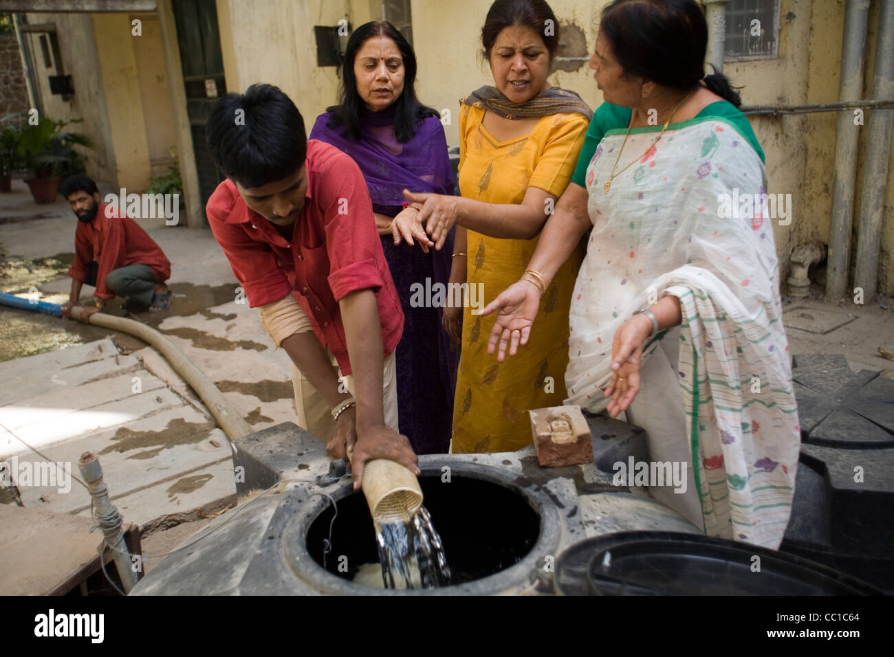 Hausfrauen im Bereich Vasant Kunj warten, Wasser in ihre Wassertanks aus einem Tankwagen gepumpt werden Stockfoto