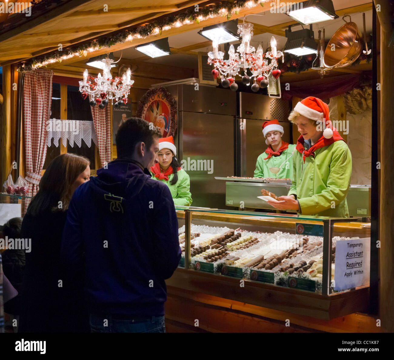 Junges Paar vor einem Stall zu verkaufen Schokolade auf dem Frankfurter deutschen Weihnachtsmarkt, New Street, Birmingham, UK Stockfoto