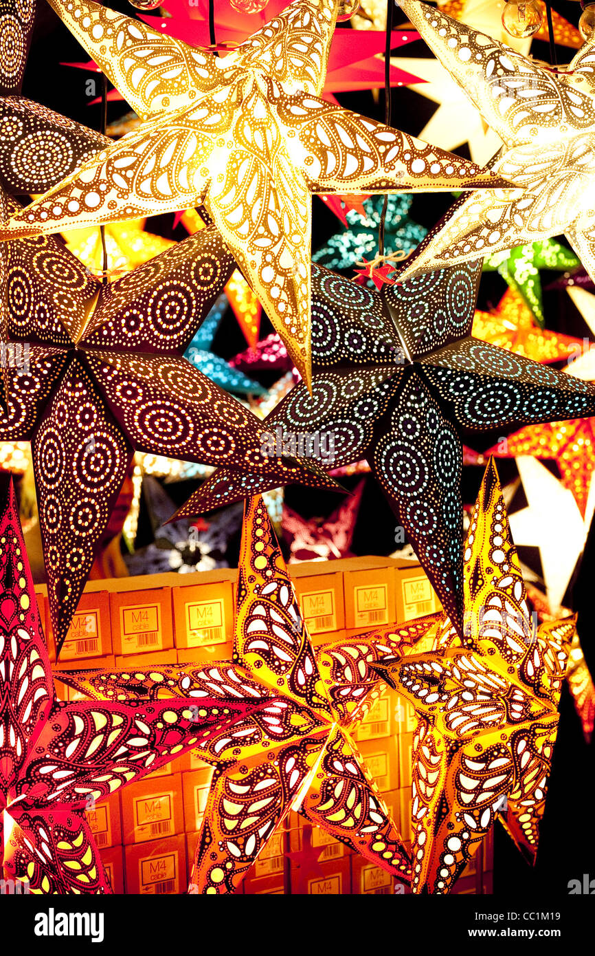 Hell, farbenfroh und dynamisch beleuchtet Papier Sterne hängen in einen Weihnachtsmarkt in München. Stockfoto