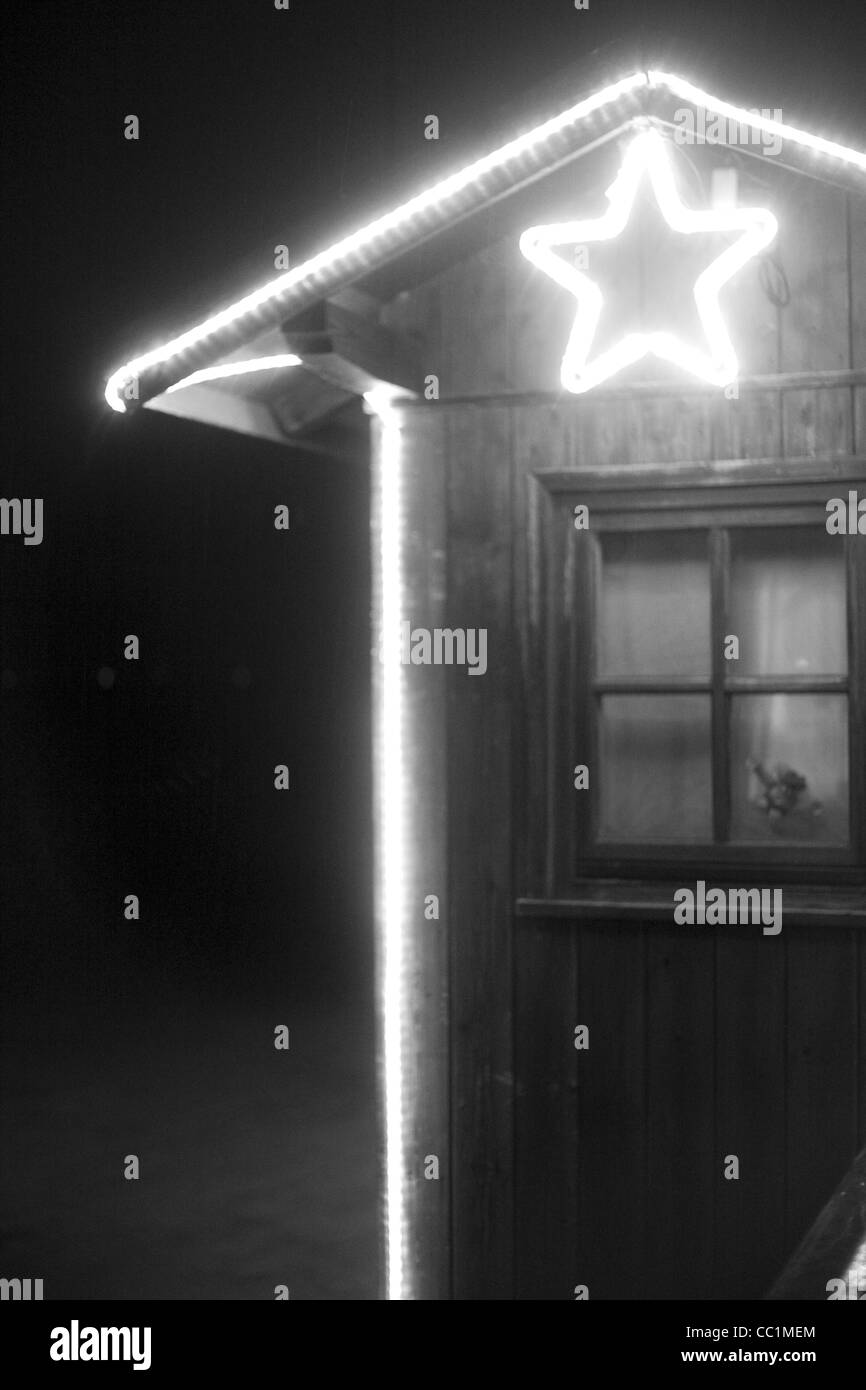 Schwarz / weiß Bild von einem Outdoor-Stand mit einem Fenster, das mit Weihnachtsbeleuchtung und einen beleuchteten Stern verziert ist. Stockfoto