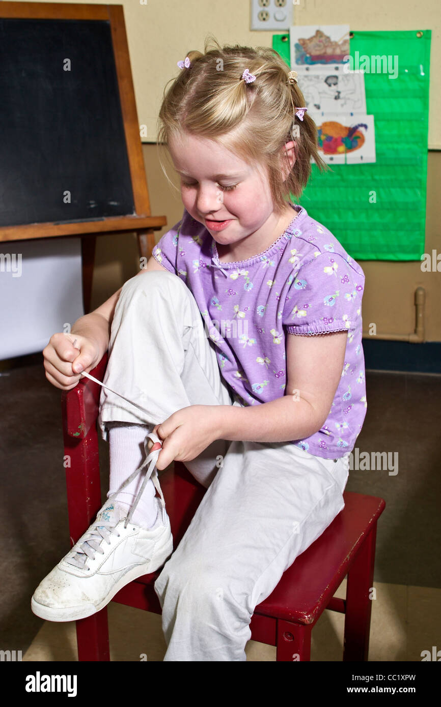 4-5 Jahre jährige kaukasische Mädchen lernen, ihre Schuhe im Klassenzimmer zu binden. Herr © Myrleen Pearson Stockfoto