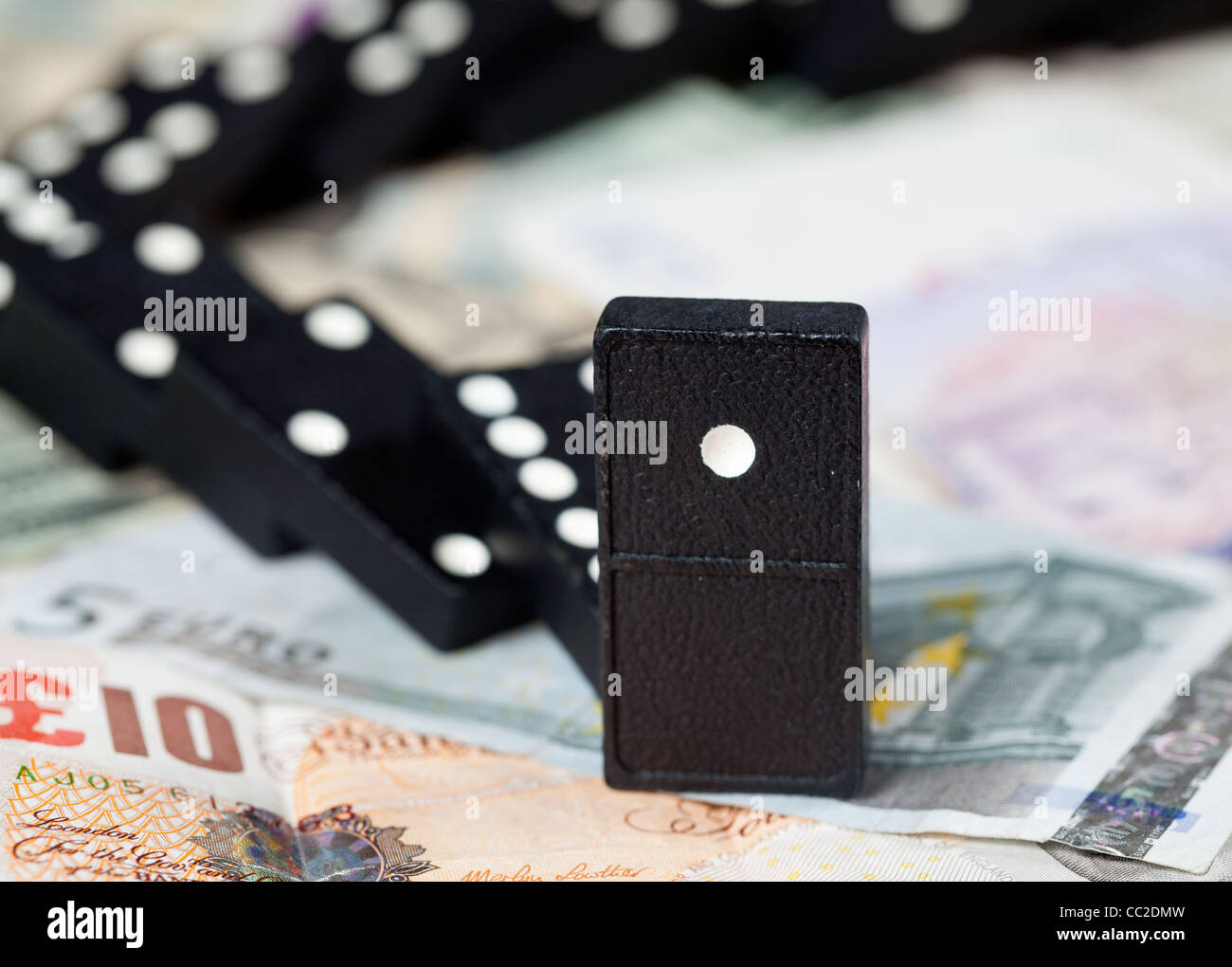 Gefallenen Dominos auf Pfund, Euro und Dollar-Banknoten, die zur Veranschaulichung Bankenkrise Stockfoto