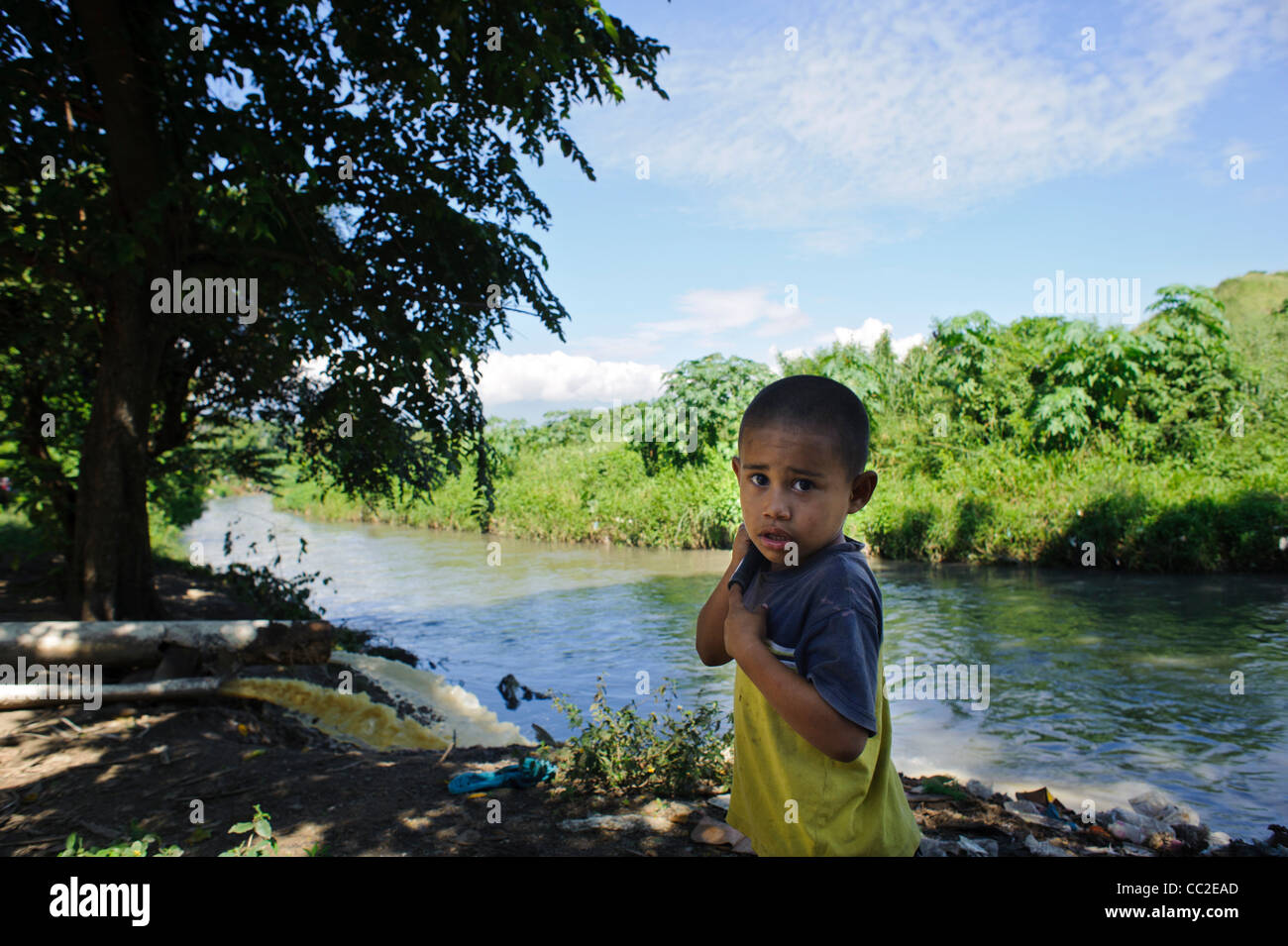 Verunreinigung des Wassers mit kleinen Jungen neben Abwasser Rohr Entwässerung in Fluss in San Pedro Sula Stockfoto